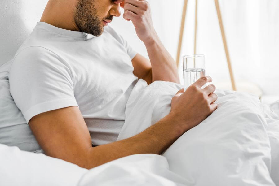 mężczyzna leży w łóżku ze szklanką wody